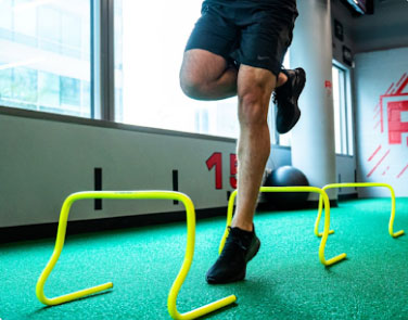 Rehab 2 perform sports rehabilitation man in sports rehab hopping over yellow jumps