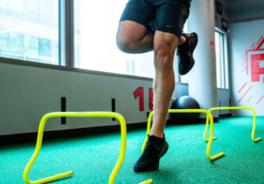 Rehab 2 perform sports rehabilitation man in sports rehab hopping over yellow jumps Rehab 2 perform sports rehabilitation man in sports rehab hopping over yellow jumps